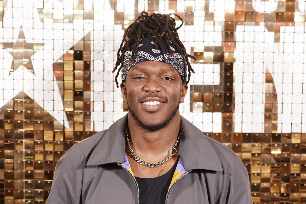 KSI posing in front of a step and repeat.